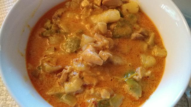 A finished bowl of yellow curry with chicken and
                        potatoes.